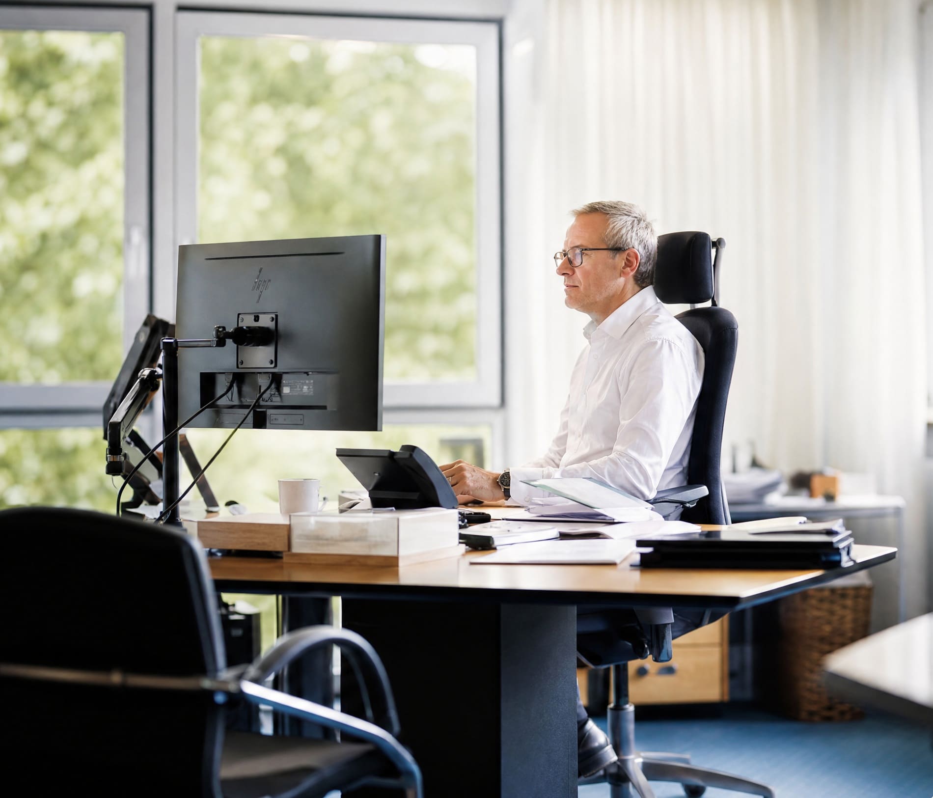 IT-Berater arbeitet konzentriert am PC-Monitor in einem modernen Büro.